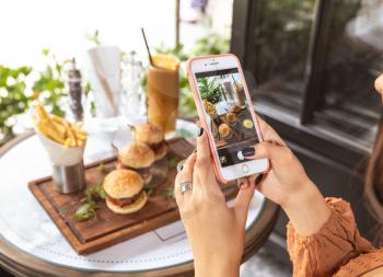 Woman taking picture of a burger menu at restaurant