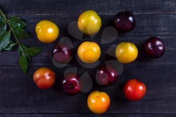 Colorful plums fruit on the black background isolated top view
