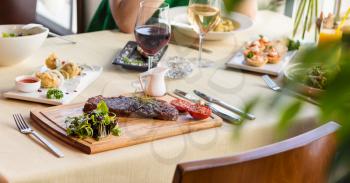 Tasty steak with vegetables on a wooden plate, garnish, red wine