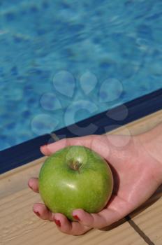 Royalty Free Photo of a Woman Holding an Apple By a Pool