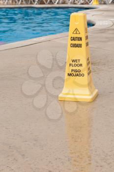 Royalty Free Photo of a Yellow Caution Sign Next to a Swimming Pool
