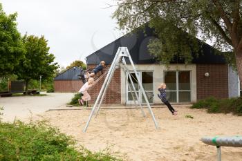 Four kids swinging on the playground on a sunny day