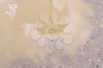 A shadow of a basketball hoop in a rain puddle
