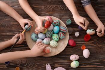 Cute little children painting eggs for Easter at table�