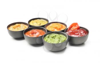 Different tasty sauces in bowls on white background�