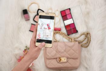 Closeup view of woman taking photo of cosmetics and accessories with mobile phone�