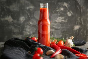 Bottle with tasty tomato sauce and vegetables on table�