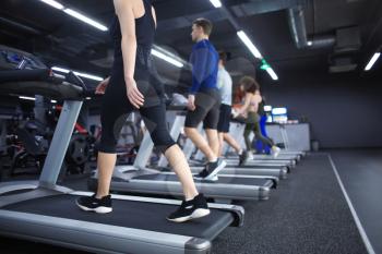 Young people running on treadmill in gym�