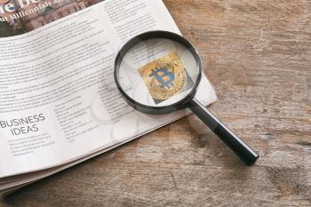 Magnifying glass and newspaper on wooden background�