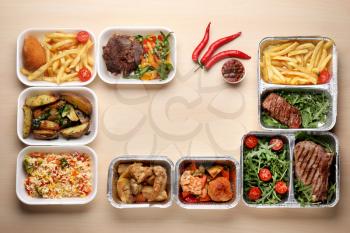 Different containers with delicious food on wooden table. Delivery service�