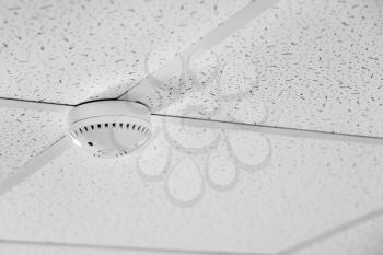 Modern smoke detector on ceiling indoors�