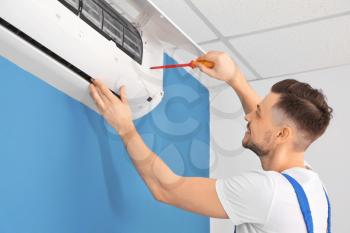 Electrician repairing air conditioner indoors�