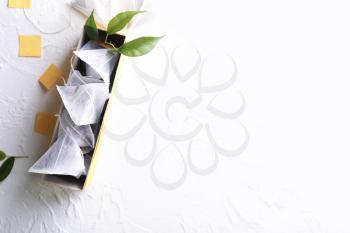 Box with tea bags on white textured background�
