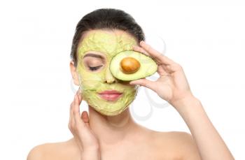 Beautiful young woman with facial mask and fresh avocado on white background�