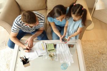 Family with pay bills, calculator and money counting expenses indoors. Money savings concept�