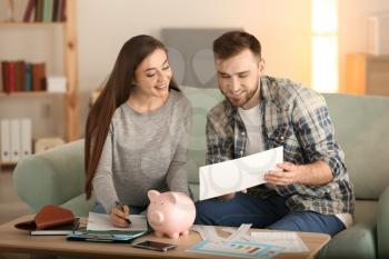 Happy couple with pay bills, calculator and money counting expenses indoors. Money savings concept�