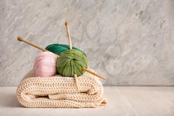 Knitting yarn with needles and scarf on wooden table�