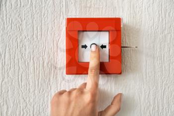 Young woman using fire alarm system indoors�