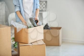 Woman packing carton box indoors. Moving house concept�