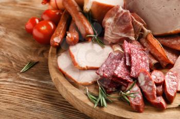 Wooden board with assortment of delicious deli meats on wooden board�