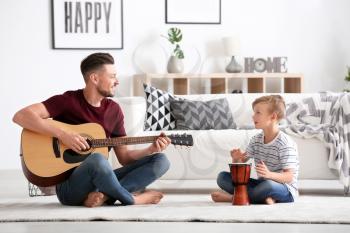 Little boy and his dad with music instruments playing at home�