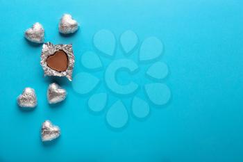 Heart-shaped chocolate candies on color background�