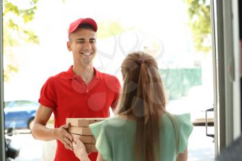 Young man giving pizza boxes to woman at doorway. Food delivery service�
