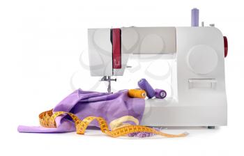 Modern sewing machine with tailor's supplies on white background�