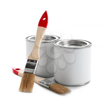 Cans of paint and brushes on white background�