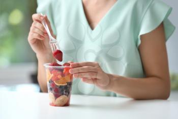 Woman eating fresh berries and fruits indoors, closeup�