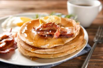 Plate with tasty pancakes and bacon on wooden table, closeup�