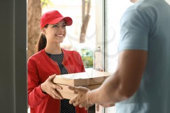 Young woman delivering pizza to customer at doorway�