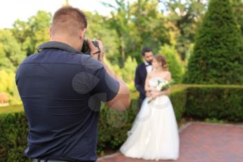 Professional photographer taking photo of wedding couple outdoors�