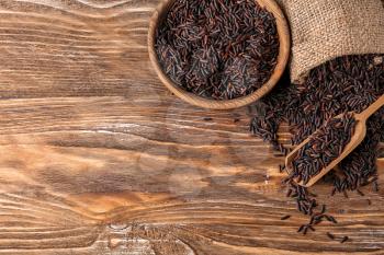 Composition raw wild rice on wooden background�