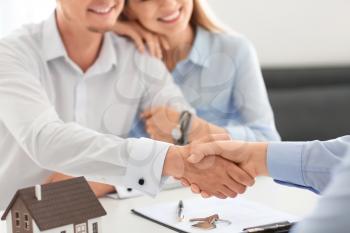 Man shaking hands with real estate agent in office�