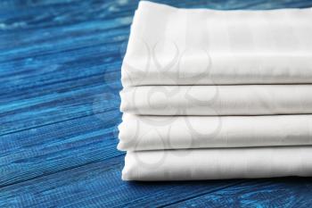 Stack of clean bed sheets on color wooden background, closeup�