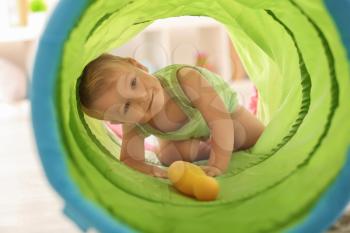 Cute little boy playing with toy tunnel at home�