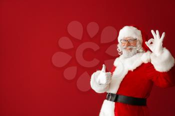 Portrait of Santa Claus showing thumb-up and OK gesture on color background�