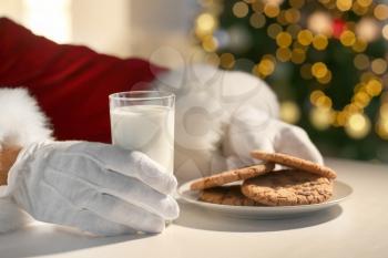 Santa Claus eating cookies and drinking milk at table, closeup�