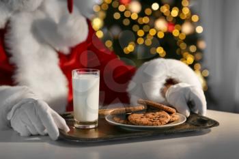 Santa Claus eating cookies and drinking milk at table, closeup�