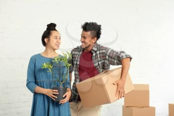 Happy interracial couple unpacking boxes in room. Moving into new house�