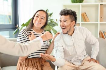 Real estate agent giving key from new house to happy couple in office�
