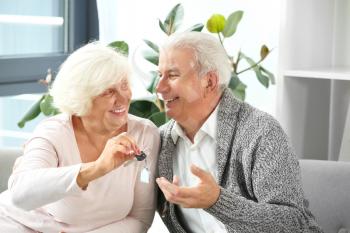 Mature couple with key from their new house in office of real estate agent�