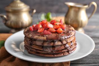 Tasty chocolate pancakes with sweet sauce and cut strawberry on plate�