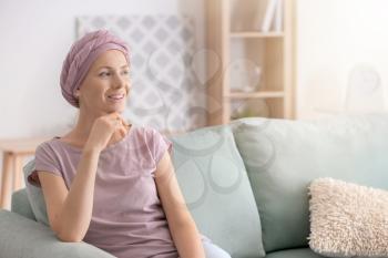Happy woman after chemotherapy  sitting on sofa at home�