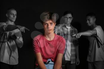 Teenagers bullying boy on dark background�