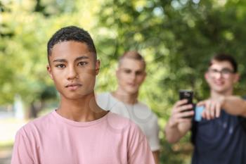 Bullied African-American teenage boy outdoors�