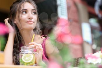Young woman drinking fresh lemonade in cafe�