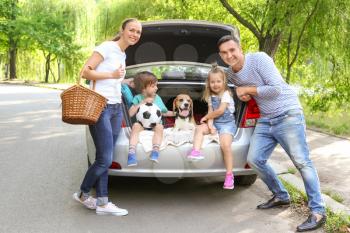 Happy family with beagle dog near car outdoors�