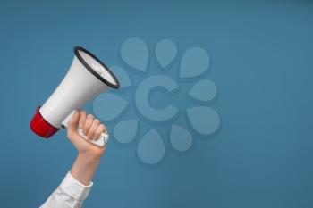 Woman holding megaphone on color background�